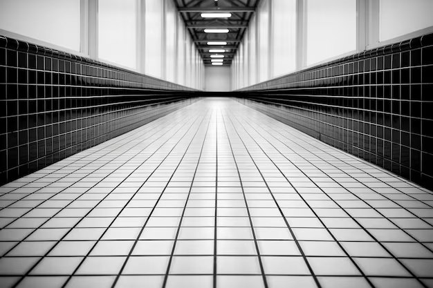 Черно-белый коридор с контрастными плитками и современным освещением. Черно-белое изображение длинного коридора с белыми и черными плитками на полу и стенах.