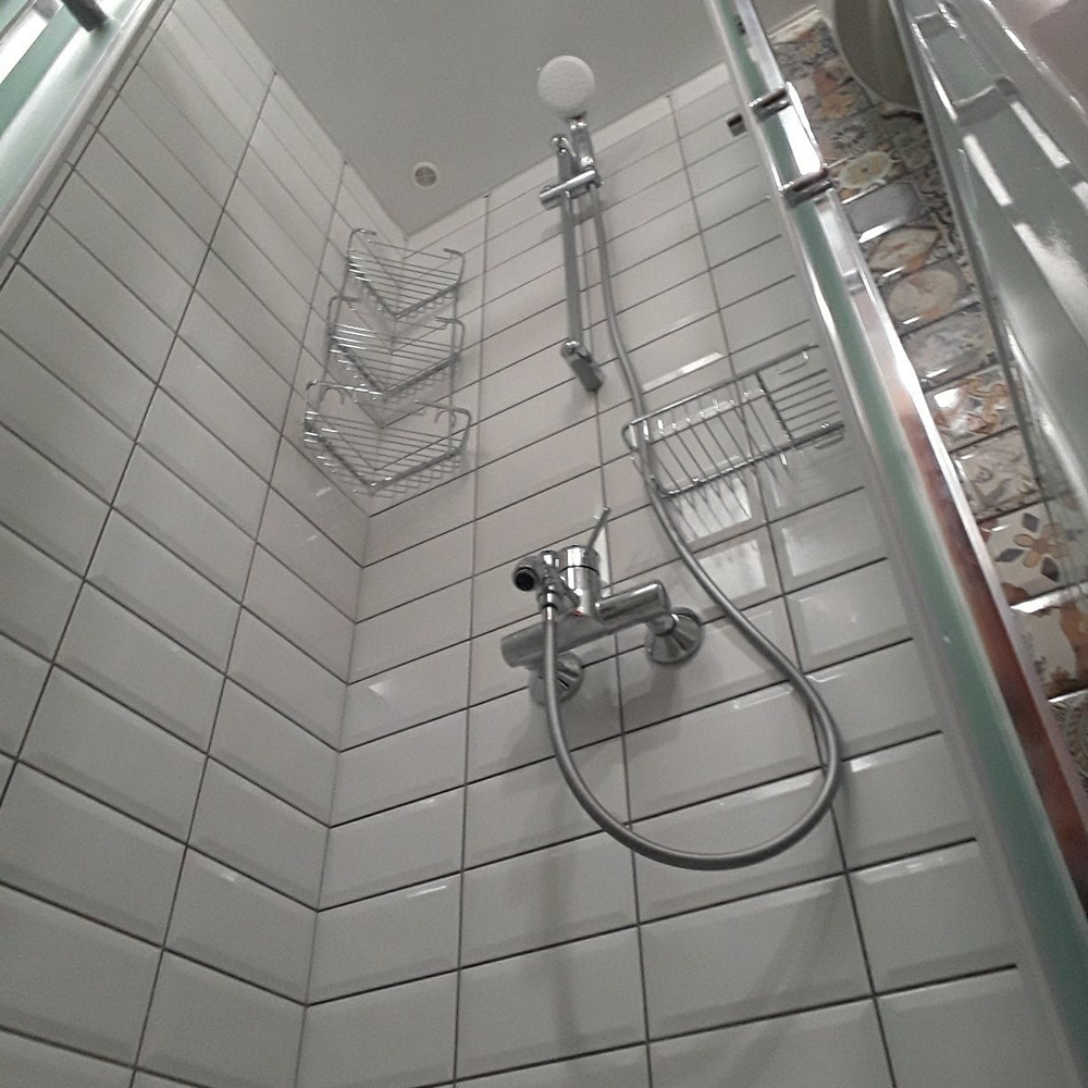 Ванная комната с душевой кабиной Ванная комната с душевой кабиной, облицованной белой плиткой.