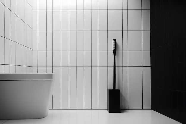 Ванная комната с белой плиткой и унитазом, на полу стоит черный ершик Ванная комната с белой плиткой на стенах и  унитазом. На полу - ершик